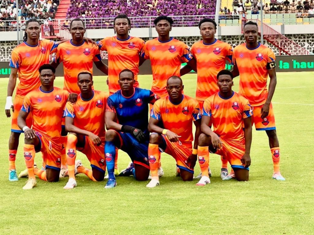 Ăquipe de football en maillots orange, posant sur le terrain avant un match.
